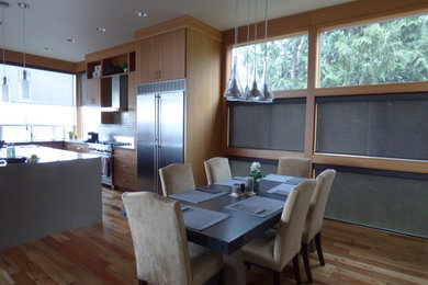 This is an example of a mid-sized modern l-shaped eat-in kitchen in Portland with light hardwood floors, a double-bowl sink, flat-panel cabinets, light wood cabinets, solid surface benchtops, multi-coloured splashback, subway tile splashback, stainless steel appliances and with island.