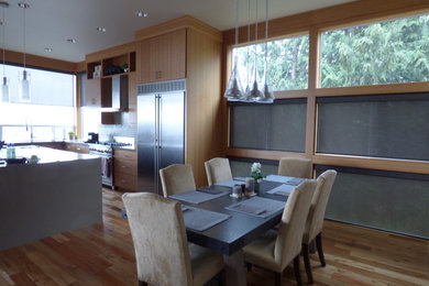 Inspiration for a mid-sized modern l-shaped light wood floor eat-in kitchen remodel in Portland with a double-bowl sink, flat-panel cabinets, light wood cabinets, solid surface countertops, multicolored backsplash, subway tile backsplash, stainless steel appliances and an island