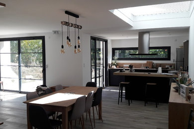 Photo of a mid-sized contemporary u-shaped eat-in kitchen in Angers with an undermount sink, beaded inset cabinets, black cabinets, wood benchtops, timber splashback, panelled appliances, light hardwood floors, with island and beige floor.