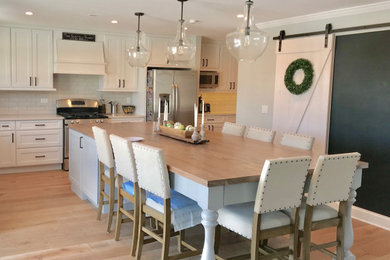 Kitchen - mid-sized country light wood floor kitchen idea in Chicago with shaker cabinets, quartz countertops, white backsplash, ceramic backsplash, stainless steel appliances, an island and white countertops