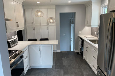 Mid-sized elegant vinyl floor and gray floor kitchen photo in Other with an undermount sink, shaker cabinets, white cabinets, quartzite countertops, gray backsplash, ceramic backsplash, stainless steel appliances and white countertops