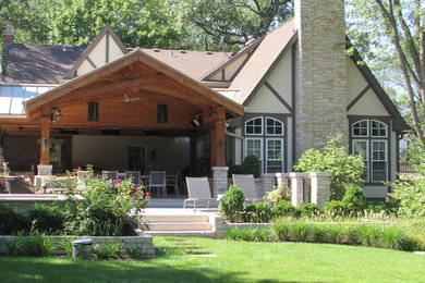 Patio kitchen - large traditional backyard stone patio kitchen idea with a roof extension