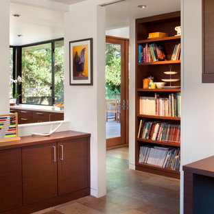 Exempel på ett mellanstort modernt hemmabibliotek, med vita väggar, skiffergolv, ett inbyggt skrivbord och brunt golv