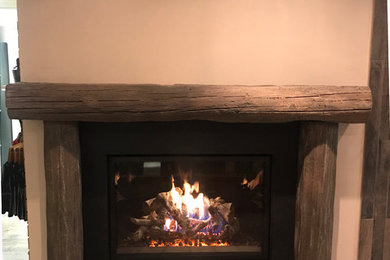 Photo of a country family room in Philadelphia with beige walls, slate floors, a standard fireplace, a concrete fireplace surround and black floor.