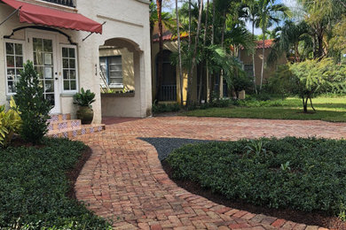Photo of a small mediterranean front yard full sun driveway in Miami with a garden path and brick pavers.