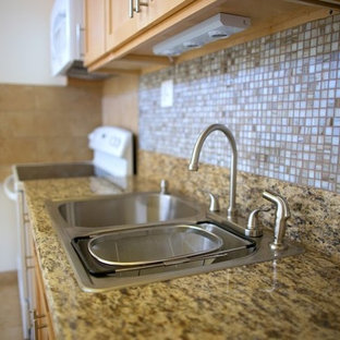 Foto på ett stort tropiskt linjärt skafferi, med en nedsänkt diskho, luckor med infälld panel, skåp i mellenmörkt trä, granitbänkskiva, beige stänkskydd, stänkskydd i mosaik, rostfria vitvaror, klinkergolv i keramik och en köksö