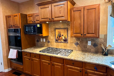 Open concept kitchen - mid-sized traditional u-shaped open concept kitchen idea in Atlanta with raised-panel cabinets, medium tone wood cabinets, quartz countertops, brown backsplash, travertine backsplash, stainless steel appliances, an island and brown countertops