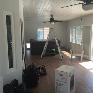 Foto de salón para visitas tipo loft, mediterráneo, de tamaño medio, con paredes blancas, suelo de madera clara, chimeneas suspendidas, marco de chimenea de piedra y pared multimedia