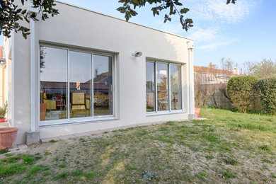 Aménagement d'une façade de maison beige contemporaine de taille moyenne et de plain-pied avec un revêtement mixte et un toit plat.