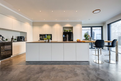 Offene Moderne Küche mit weißen Schränken, Kücheninsel und grauer Arbeitsplatte in Sonstige
