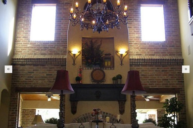 Huge trendy open concept limestone floor living room photo in Houston with beige walls and a plaster fireplace