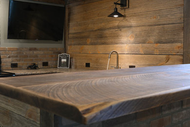 Photo of a mid-sized country galley seated home bar in Minneapolis with a drop-in sink, raised-panel cabinets, light wood cabinets, wood benchtops, timber splashback and brown benchtop.