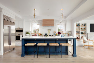 Transitional l-shaped light wood floor and beige floor kitchen photo in San Francisco with recessed-panel cabinets, white cabinets, white backsplash, stainless steel appliances, an island and white countertops