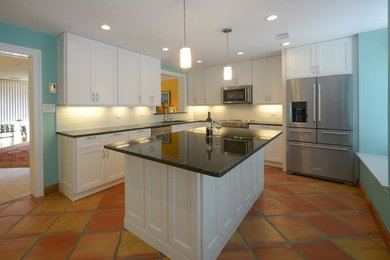 Example of a mid-sized transitional l-shaped terra-cotta tile and brown floor enclosed kitchen design in DC Metro with shaker cabinets, white cabinets, granite countertops, white backsplash, an island, an undermount sink, glass tile backsplash and stainless steel appliances