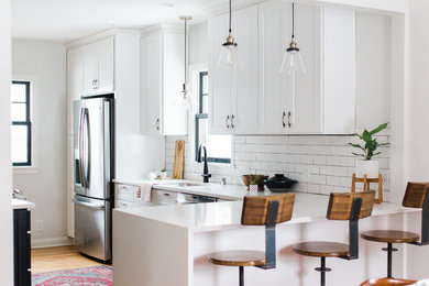 Mid-sized transitional galley light wood floor eat-in kitchen photo in Minneapolis with a double-bowl sink, shaker cabinets, white cabinets, quartz countertops, white backsplash, subway tile backsplash, stainless steel appliances and a peninsula