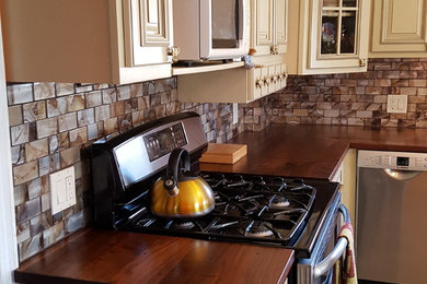 Enclosed kitchen - large craftsman l-shaped light wood floor enclosed kitchen idea in Miami with an undermount sink, beaded inset cabinets, white cabinets, wood countertops, brown backsplash, glass tile backsplash and stainless steel appliances