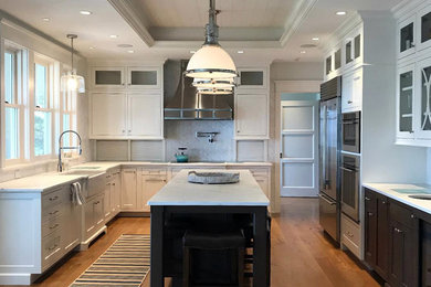 Transitional u-shaped medium tone wood floor kitchen photo in Bridgeport with a farmhouse sink, beaded inset cabinets, white cabinets, marble countertops, white backsplash, marble backsplash, stainless steel appliances, an island and white countertops
