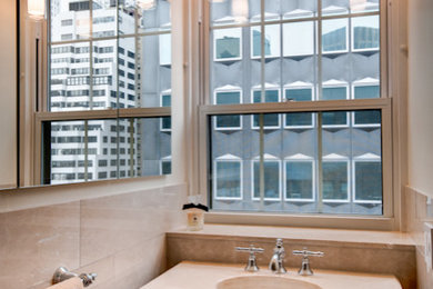 Elegant beige tile and stone tile bathroom photo in New York with beige cabinets, a console sink and beige countertops