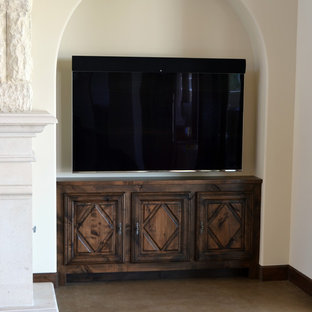 This is an example of a large mediterranean living room in Phoenix with beige walls, concrete flooring, a standard fireplace, a stone fireplace surround, a wall mounted tv and brown floors.