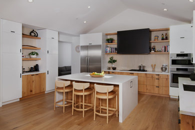 Inspiration for a huge contemporary l-shaped light wood floor, brown floor and vaulted ceiling kitchen pantry remodel in San Francisco with an undermount sink, flat-panel cabinets, light wood cabinets, quartz countertops, beige backsplash, ceramic backsplash, stainless steel appliances, an island and white countertops