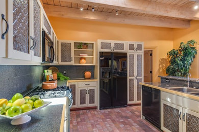 Inspiration for a mid-sized southwestern l-shaped brick floor eat-in kitchen remodel in Albuquerque with a double-bowl sink, glass-front cabinets, beige cabinets, laminate countertops, gray backsplash, an island, porcelain backsplash and black appliances
