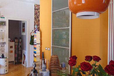 Immagine di un soggiorno design di medie dimensioni e aperto con libreria, pareti beige, parquet chiaro, camino bifacciale, cornice del camino in intonaco, TV autoportante e pavimento beige