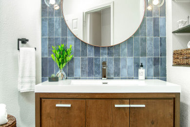 Small transitional kids' blue tile ceramic tile and single-sink shower curtain photo in Dallas with furniture-like cabinets, medium tone wood cabinets, a one-piece toilet, white walls, an integrated sink, white countertops, a niche and a freestanding vanity