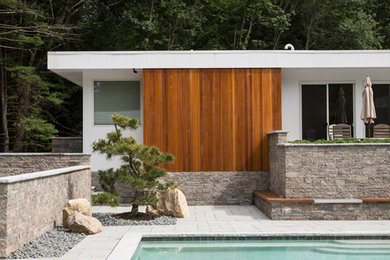 Inspiration for a mid-sized contemporary backyard custom-shaped pool in Boston with a pool house and tile.