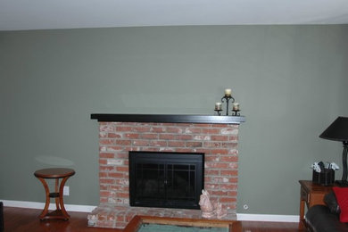 Example of a classic medium tone wood floor family room design in San Francisco with green walls, a standard fireplace, a brick fireplace and no tv