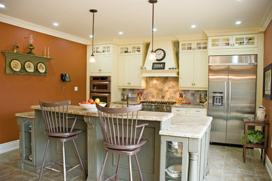 Mid-sized country galley slate floor eat-in kitchen photo in Toronto with an undermount sink, shaker cabinets, yellow cabinets, granite countertops, multicolored backsplash, stone tile backsplash, stainless steel appliances and an island