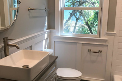 Mid-sized transitional white tile and subway tile pebble tile floor and multicolored floor bathroom photo in New York with raised-panel cabinets, gray cabinets, a two-piece toilet, gray walls, a drop-in sink and quartz countertops