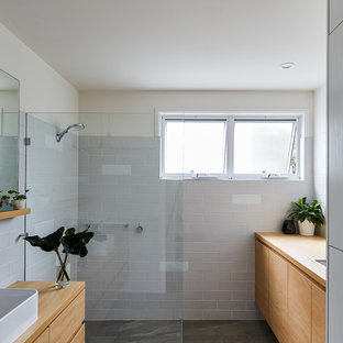 Photo of a small beach style bathroom in Gold Coast - Tweed with white tile, gray tile, subway tile, a vessel sink, wood benchtops, grey floor, flat-panel cabinets, medium wood cabinets, a curbless shower, beige walls, an open shower and brown benchtops.