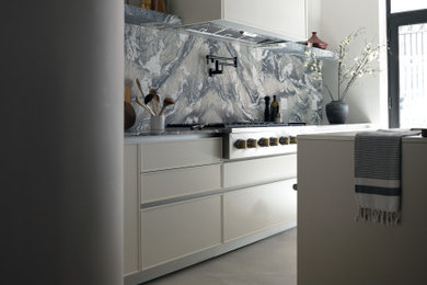 Example of a large trendy cement tile floor and gray floor open concept kitchen design in New York with beige cabinets, marble countertops, marble backsplash and an island