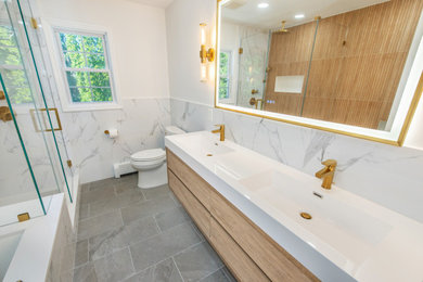Example of a mid-sized 1950s master white tile and stone slab ceramic tile, gray floor and double-sink bathroom design in Newark with flat-panel cabinets, light wood cabinets, an undermount tub, a one-piece toilet, white walls, an integrated sink, quartzite countertops, white countertops, a niche and a floating vanity
