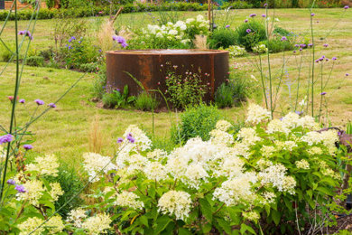 Ejemplo de jardín campestre grande en patio trasero con parterre de flores y exposición total al sol