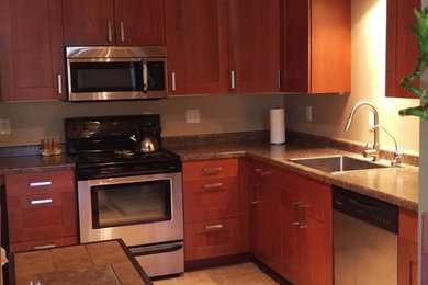 Mid-sized minimalist l-shaped ceramic tile eat-in kitchen photo in Minneapolis with a drop-in sink, flat-panel cabinets, medium tone wood cabinets, granite countertops, stainless steel appliances and an island