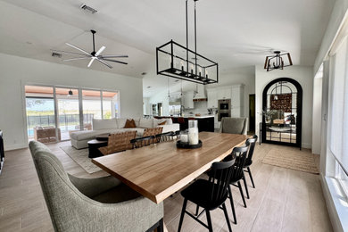Example of a large transitional porcelain tile, brown floor and vaulted ceiling kitchen/dining room combo design in Miami with white walls