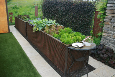 Großer Moderner Gemüsegarten hinter dem Haus mit Natursteinplatten