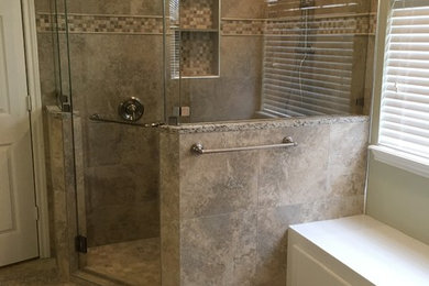 Photo of a traditional master bathroom in Houston with recessed-panel cabinets, white cabinets, a corner shower, beige tile, porcelain tile, green walls, porcelain floors, brown floor and a hinged shower door.