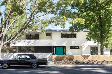 Example of a 1960s white two-story house exterior design in Sacramento with a hip roof and a shingle roof