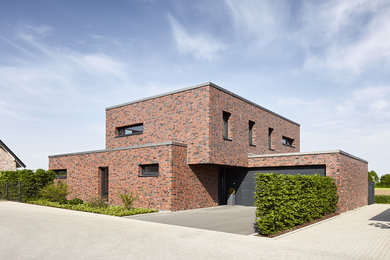 Large contemporary two-storey brick red exterior in Dusseldorf with a flat roof.