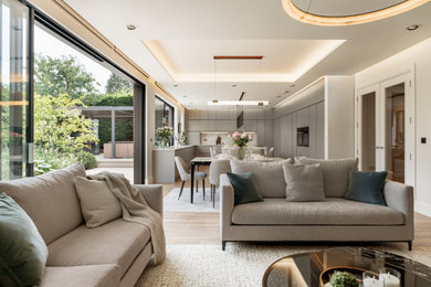Inspiration for an expansive contemporary grey and white u-shaped open plan kitchen in Other with a submerged sink, flat-panel cabinets, grey cabinets, composite countertops, grey splashback, engineered quartz splashback, black appliances, ceramic flooring, an island, brown floors, grey worktops, a coffered ceiling and feature lighting.