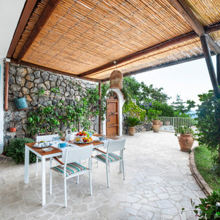 Ispirazione per un grande patio o portico mediterraneo davanti casa con pavimentazioni in pietra naturale e una pergola
