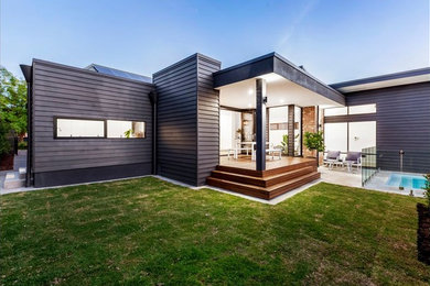 Photo of a gey modern bungalow house exterior in Adelaide with wood cladding and a flat roof.