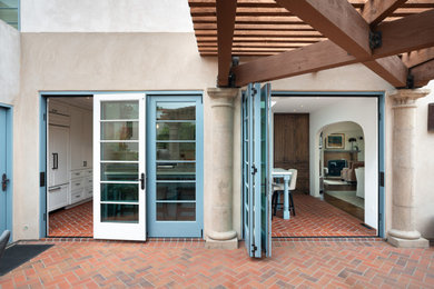 Inspiration for a huge mediterranean brick floor and red floor sliding front door remodel in San Diego with white walls and a blue front door