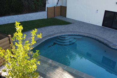 Example of a mid-sized minimalist backyard stamped concrete and rectangular pool design in Los Angeles