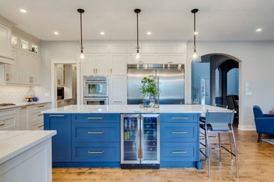 Large minimalist u-shaped light wood floor and beige floor eat-in kitchen photo in Calgary with an undermount sink, shaker cabinets, white cabinets, quartz countertops, white backsplash, porcelain backsplash, stainless steel appliances, an island and white countertops