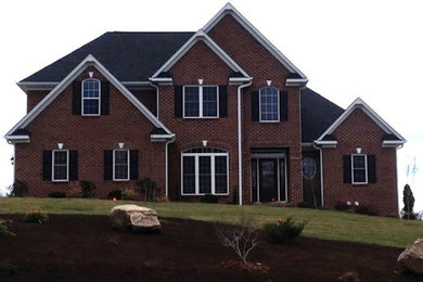 Large red two-story exterior home photo in Other