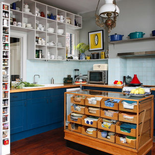 Imagen de cocina en L, bohemia, con fregadero encastrado, armarios estilo shaker, puertas de armario azules, encimera de madera, salpicadero azul, salpicadero de azulejos de cerámica, suelo de madera oscura y una isla