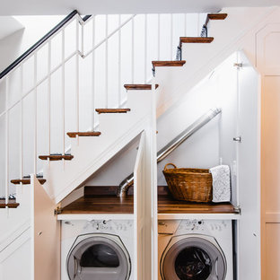 ワシントンD.C.の中サイズのトラディショナルスタイルのおしゃれなランドリークローゼット (シェーカースタイル扉のキャビネット、白いキャビネット、木材カウンター、白い壁、濃色無垢フローリング、目隠し付き洗濯機・乾燥機、茶色い床、茶色いキッチンカウンター) の写真